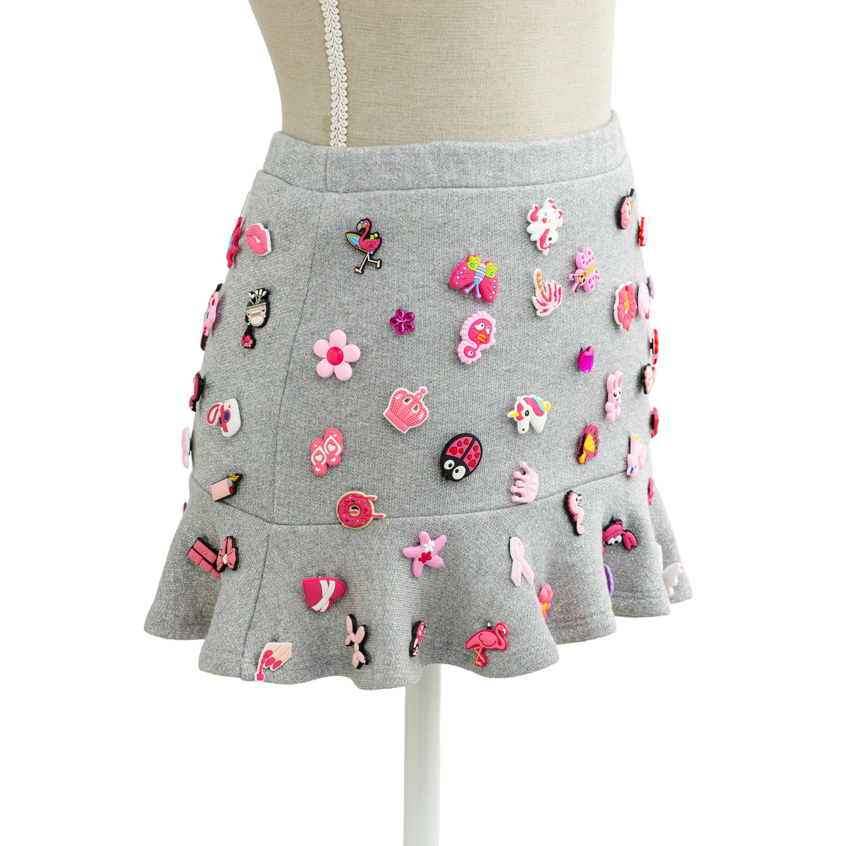 Charm mini skirt in grey with pink charms, styled on a mannequin