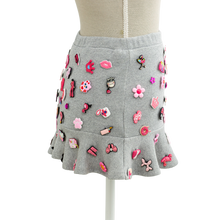 Side view of the grey charm mini skirt with a flared ruffle hem