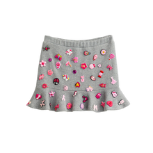 Grey charm mini skirt with removable pink charms and a ruffle hem, front view